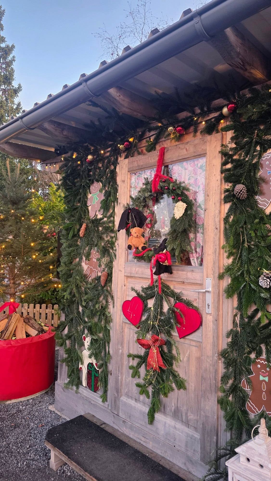 Ezt a rusztikus stílusú ajtódíszt fenyőágak, tobozok és élénkpiros masnik díszítik. - Z(s)eppelin utazás