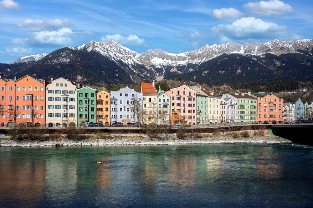 Ez a fénykép az ausztriai Innsbruck városát ábrázolja, ahol a történelmi, színes Mariahilfstraße házai sorakoznak az Inn folyó partján. - Z(s)eppelin utazás