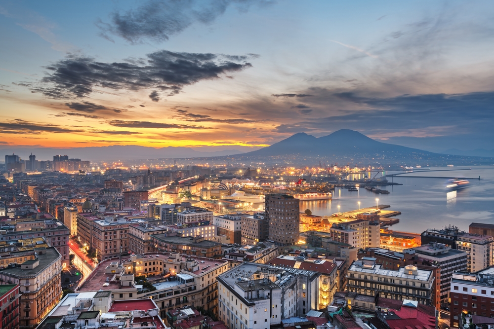 A képen Nápoly panorámája látható a Vezúvval a háttérben, naplementekor.  - Z(s)eppelin utazás